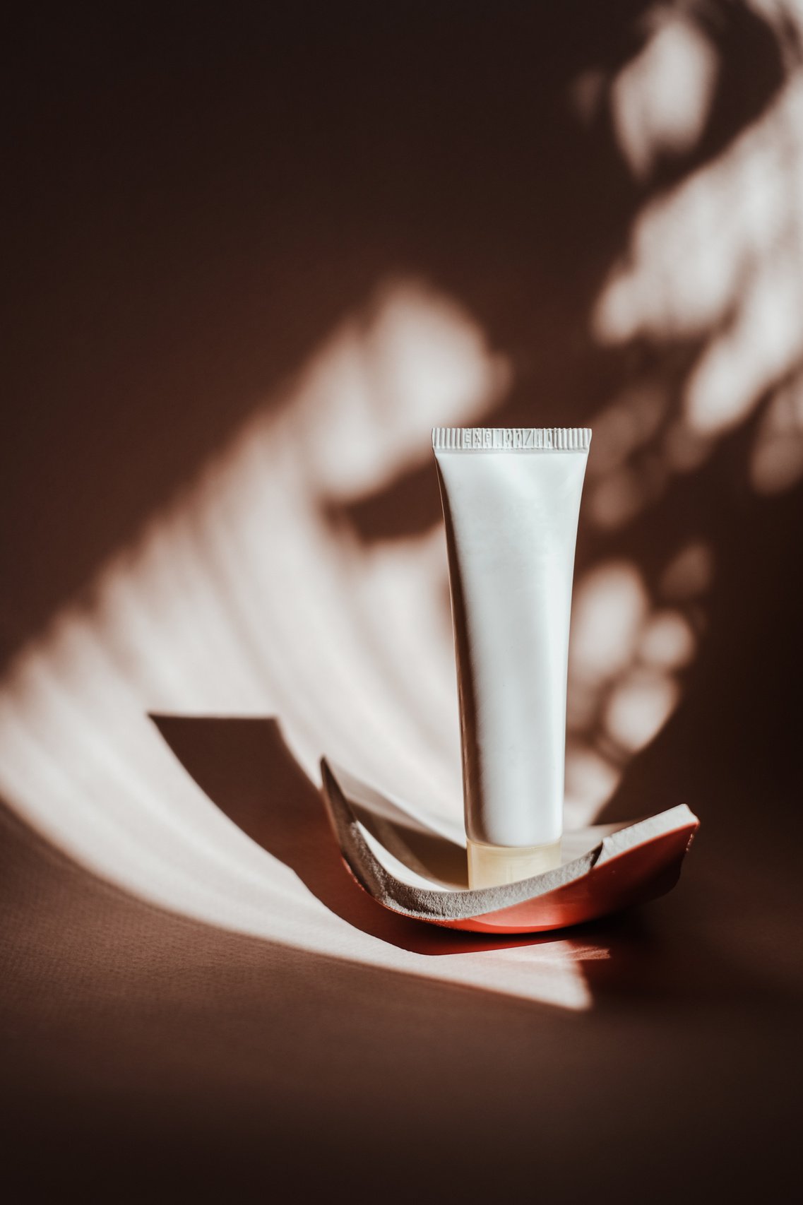 White Cosmetic Tube on Brown Background with Shadow